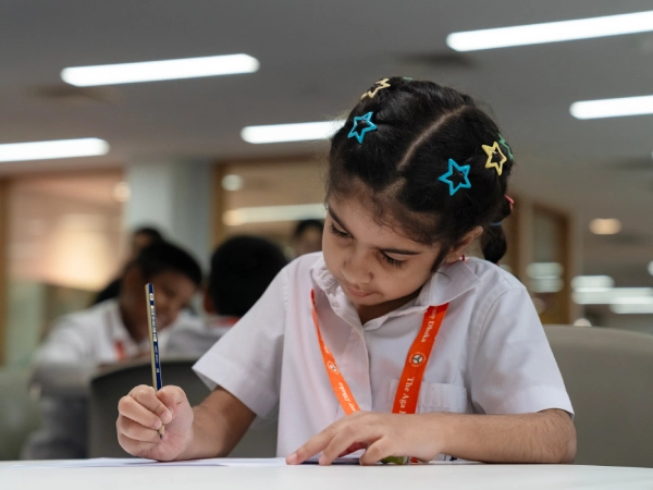 A young student focuses on her writing during a classroom activity at AKA Dhaka.